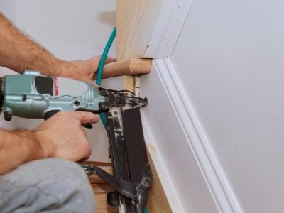 Carpenter brad using nail gun to Moulding trim